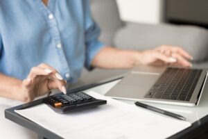 Hands,Of,Mature,Accountant,Lady,Typing,On,Calculator,And,Laptop,